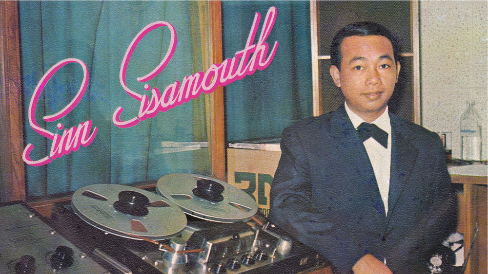 A male musician wearing a tux stands beside recording equipment with the words Sinn Sisamouth written in pink cursive on the top left. 